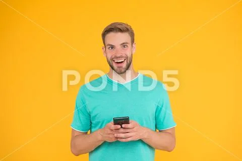 Download application. Guy play game on smartphone. Guy smiling face play game Stock Photos