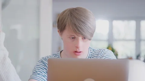 Downs Syndrome Man Sitting With Female Home Tutor Using Laptop For Lesson At Stock Footage