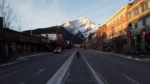 Downtown Banff, Alberta sits beneath Cascade Mountain at dusk Stock Footage 119979929