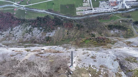 Downward angle drone shot of BASE jumper with a wingsuit off a steep mountain Stock Footage 296590335