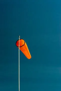 Downward angled plain orange windsock against a clear blue sky. Stock Photos