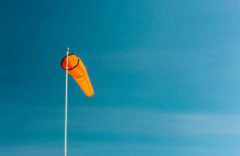 Downward angled plain orange windsock against a clear blue sky. Stock Photos