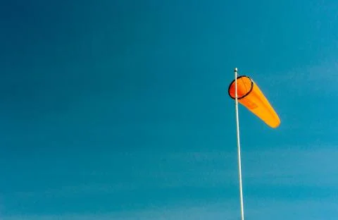 Downward angled plain orange windsock against a clear blue sky. Stock Photos