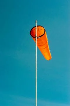 Downward angled plain orange windsock against a clear blue sky. Stock Photos