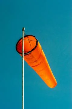 Downward angled plain orange windsock against a clear blue sky. Stock Photos