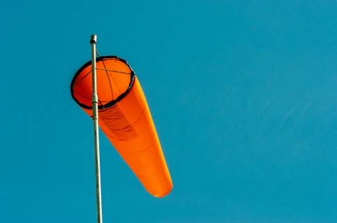 Downward angled plain orange windsock against a clear blue sky. Stock Photos