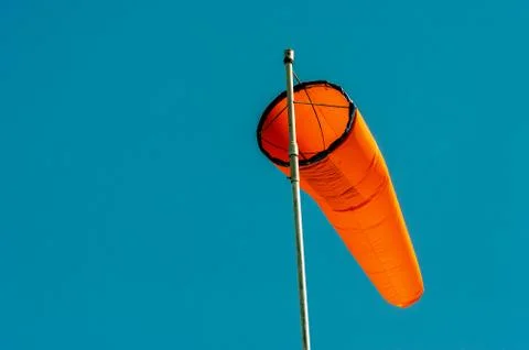 Downward angled plain orange windsock against a clear blue sky. Stock Photos