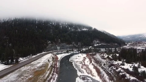 Downward crane shot over river with snow on bank and empty highway with fog Stock Footage 125278018