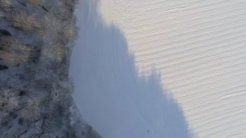 Downwards facing shot of snow covered forrest and fields at sunny winter day  Stock Footage 103263088