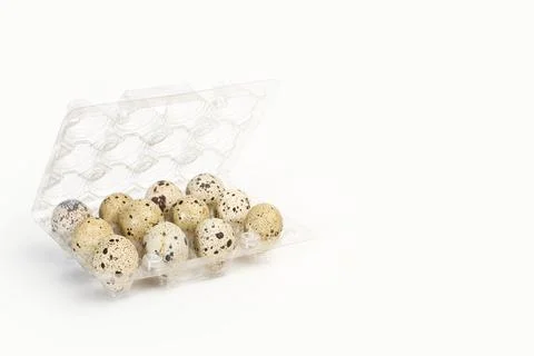 A dozen of quail eggs in a plastic tray on a white background with copy space Foto stock
