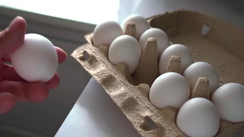 A dozen white chicken eggs in a catron box on the kitchen table Stock Footage 246704624