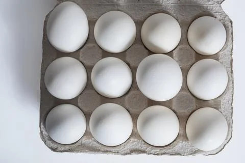 Dozen white eggs in a paper egg carton on a table. Top view Stock Photos