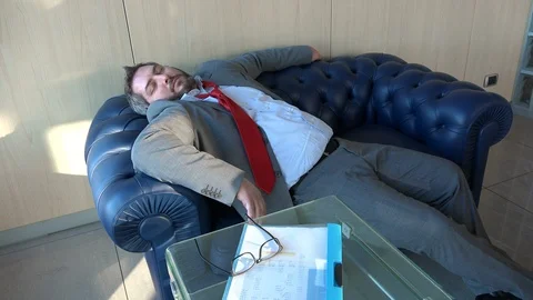 Dozy manager sleeping on sofa in office, overworked male chief lying on couch Stock Footage 102155404