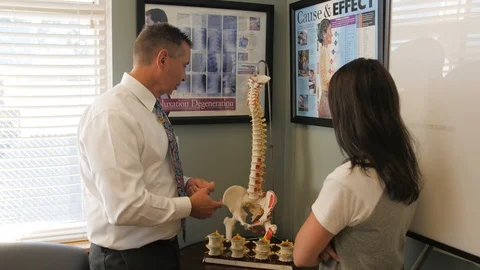 Dr turns spine model to explain Stock Footage 107765110