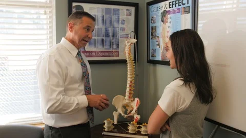 Dr uses vertebrae models to explain Stock Footage 107763542