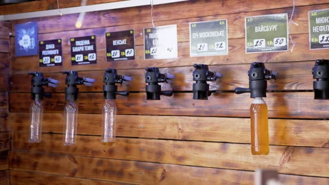 Draft Beer in Plastic Bottles Hanging on Beer Taps in Bar at Wall. Close up. 4K Stock Footage 167166057