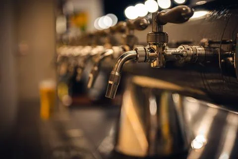 Draft beer taps in modern brewery, side view. Dark pub on a background. Foto stock