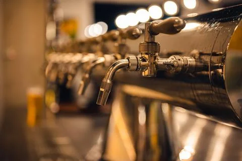 Draft beer taps in modern brewery, side view. Dark pub on a background. Foto stock