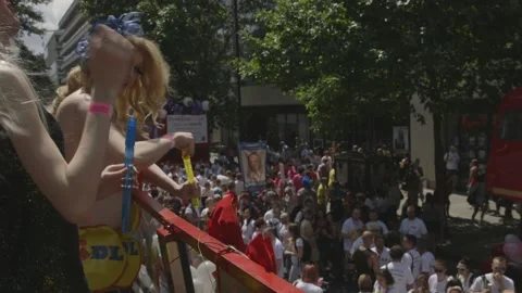 DRAG QUEENS BLOWING BUBBLES AT CROWD FROM ATOP A BUS AT PRIDE IN LONDON PARADE Stock Footage 130743090