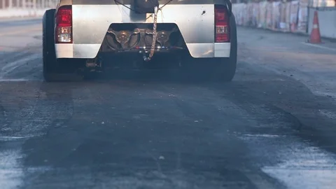 Drag racing car burns rubber off its tires in preparation for the race Stock Footage 85712922