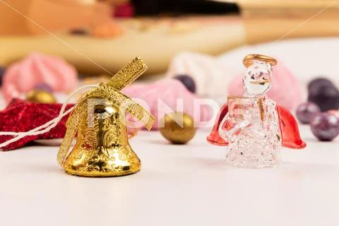 Dragee candies, bell, crystal angel and meringue cake on a white wooden table Stock Photos