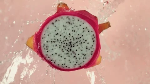 Dragon fruit half splashing into pink liquid in slow motion Stock Footage 327573545
