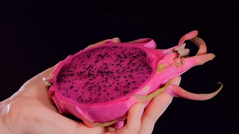 Dragon fruit or pitaya with a spoon in female hands on black background Видео 121709511