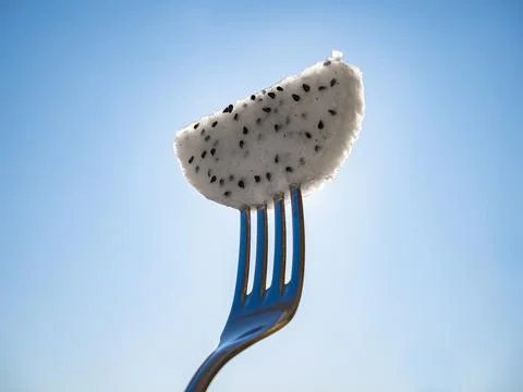 Dragon fruit slice in a fork, tropical fruit art Stock Photos