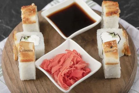 Dragon sushi rolls with eel and pickled ginger on wooden board Stock Photos