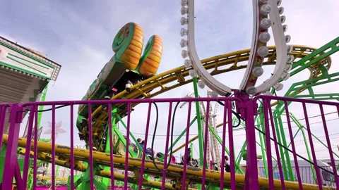 A dragon-themed roller coaster car on a yellow track at a fairground in Aveiro Stock Footage 333347280