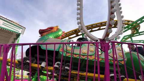 A dragon-themed roller coaster car on a yellow track at a fairground in Aveir Stock Photos