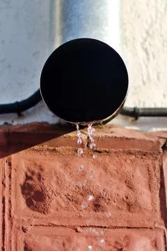 Drain downpipe on wall of house with falling drops Stock Photos