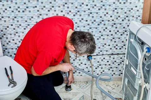 Drain hose is inserted into floor drain pipe socket and pushed down until f.. Stock Photos