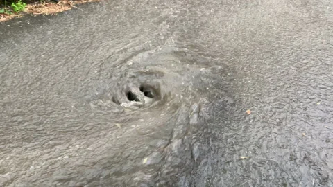 Drain manhole in stone almost full of water during heavy rain Vídeo Stock 137019616