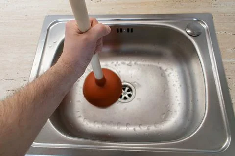 Drain Problems, blockage plumbing kitchen sink unclog plunger man hand hold Stock Photos