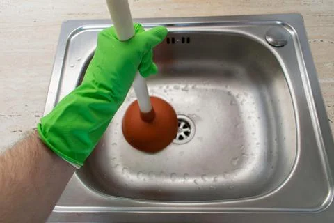 Drain Problems, blockage plumbing kitchen sink unclog plunger man hand hold Stock Photos