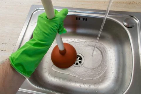 Drain Problems, blockage plumbing kitchen sink unclog plunger man hand hold Stock Photos