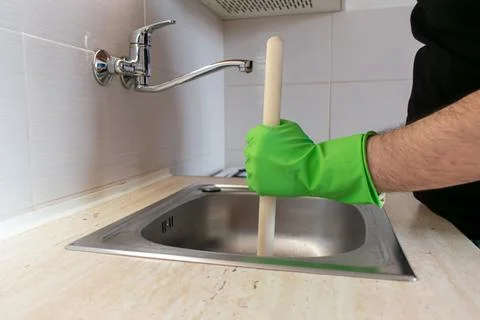 Drain Problems, blockage plumbing kitchen sink unclog plunger man hand hold Stock Photos