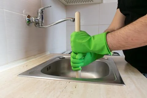 Drain Problems, blockage plumbing kitchen sink unclog plunger man hand hold Stock Photos