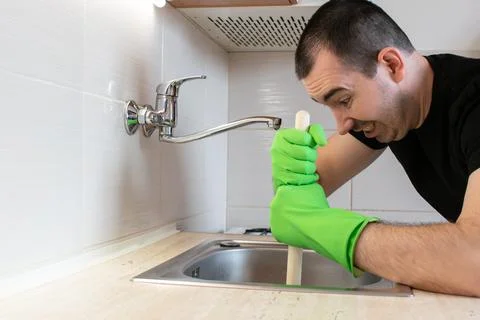 Drain Problems, blockage plumbing kitchen sink unclog plunger man hand hold Stock Photos