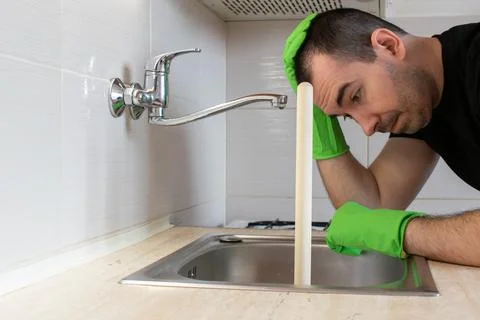 Drain Problems, blockage plumbing kitchen sink unclog plunger man hand hold Stock Photos
