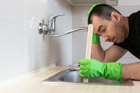 Drain Problems, blockage plumbing kitchen sink unclog plunger man hand hold Stock Photos