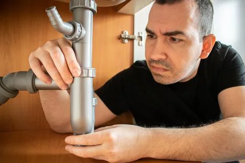 Drain Problems, blockage plumbing kitchen sink pipe unclog plunger man hand h Stock Photos