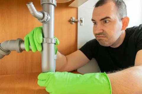 Drain Problems, blockage plumbing kitchen sink pipe unclog plunger man hand h Stock Photos