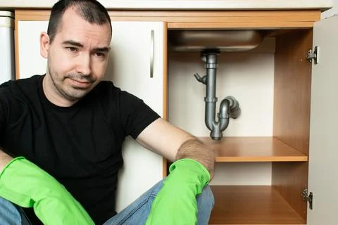 Drain Problems, blockage plumbing kitchen sink pipe unclog male man sit tired Stock Photos