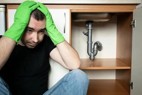 Drain Problems, blockage plumbing kitchen sink pipe unclog male man sit tired Stock Photos