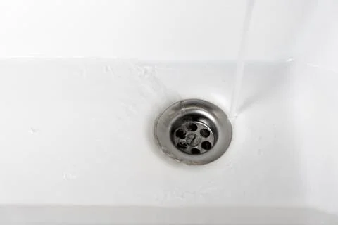 Drain in a white sink, background, close-up Stock Photos
