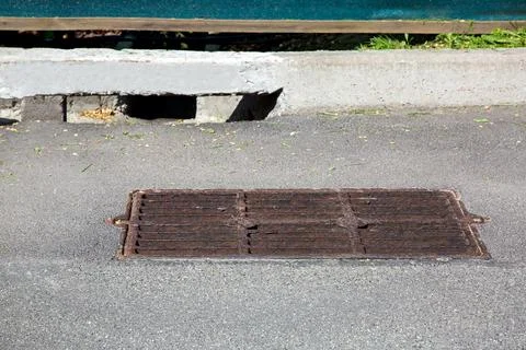 Drainage grate on a rectangular manhole on an asphalt road. Stock Photos