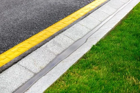 Drainage system edge tray with dripping rain water near asphalt road. Stock Photos