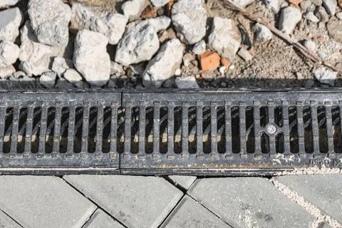 A drainage system runs along a paved area at a construction site. Small rocks Stock Photos